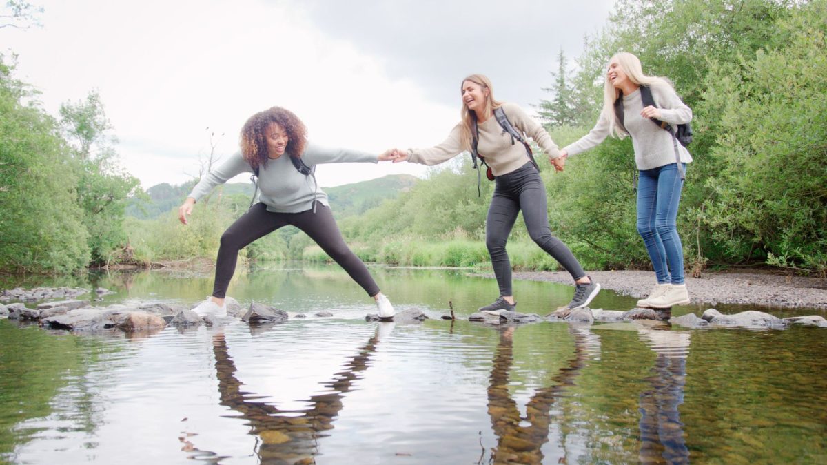 Women laughing while talking over stepping stones 